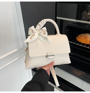 Close-up of white lychee pattern leather handbag with silk scarf and metal twist lock