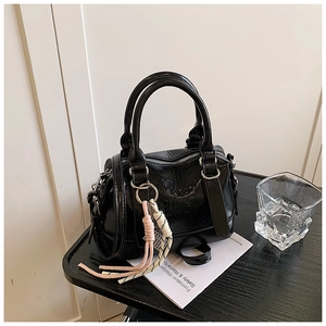 Detail of black glossy leather pillow bag with embossed letters and pink tassel