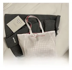 Close-up of canvas tote bag featuring red letter print and red plaid lining detail