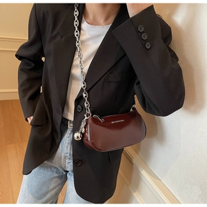 Détail du sac sous le bras en cuir verni bordeaux avec chaîne argentée et breloque en boule
