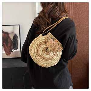 Detail view of round woven straw bag with floral pattern flap and vintage metal lock