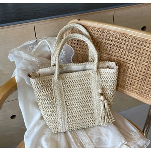 Close-up of woven tote bag featuring hollow diamond mesh pattern and tassel with wooden beads