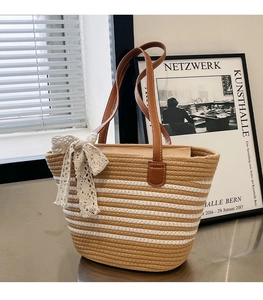 Detail of woven tote bag featuring striped pattern and cream lace bow decoration