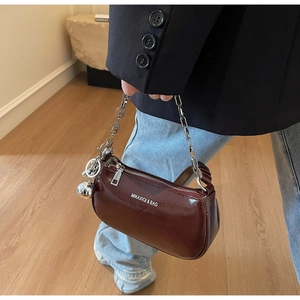 Détail du sac demi-lune rouge foncé avec chaîne argentée et pendentif boule en métal