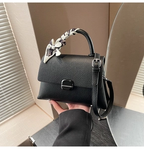 Detail of black lychee grain leather handbag with stylish floral scarf on handle
