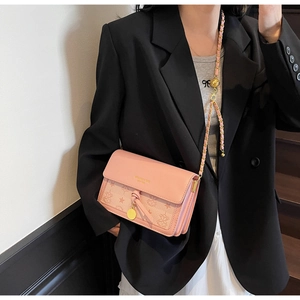 Close-up of pink embossed leather crossbody bag with gold chain and star prints