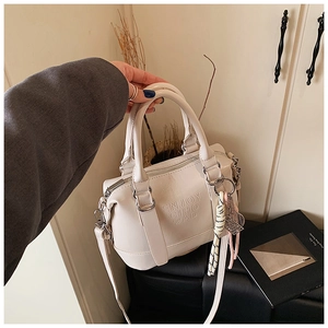 Detail of cream boston bag with soft leather texture and debossed lettering decoration