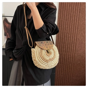 Detail of round straw bag with ethnic print leather flap and bronze metal clasp