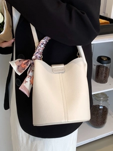 Minimalist beige bucket bag with lychee grain leather and silk scarf handle detail