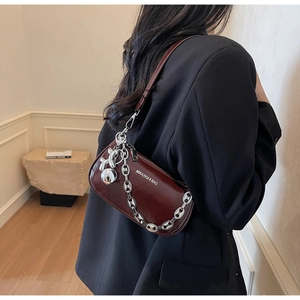 Détail du sac baguette bordeaux avec chaîne argentée et breloque chien ballon
