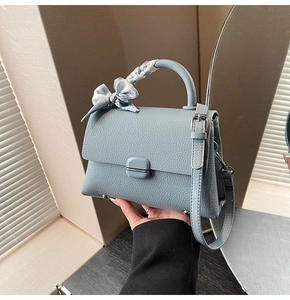 Close-up of light blue leather handbag with square buckle and silk scarf on handle