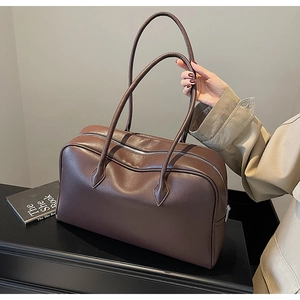 Detail of dark brown pebble leather Boston bag with long handles and silver hardware