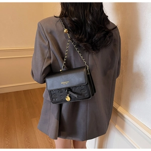 Detail view of black crossbody bag featuring embossed leather texture and gold chain strap