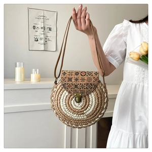 Close-up of a round straw woven bag with vintage floral pattern and metallic clasp