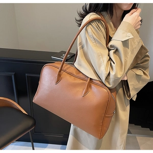 Close-up of caramel brown pebble leather tote bag texture with long shoulder straps
