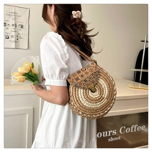 Detail view of woven round straw bag with bohemian floral flap and metal clasp closure