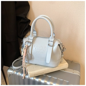 Detail of light blue soft leather Boston bag with embossed letters and tennis racket charm