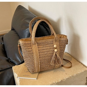 Close-up of woven straw tote bag featuring thick rope texture and large tassel detail