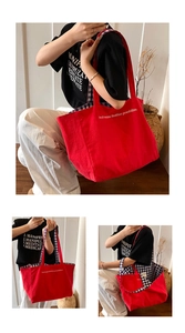 Detail of red reversible canvas tote bag showing blue checkered lining and slogan print