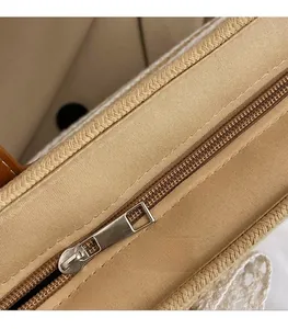 Close-up of a smooth metal zipper on a khaki woven straw tote bag with textured details