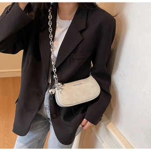 Gros plan d'un sac demi-lune beige avec chaîne argentée et charm lapin stylé