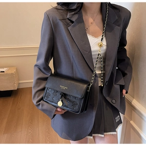 Detail of black crossbody bag featuring embossed star patterns and gold logo hardware