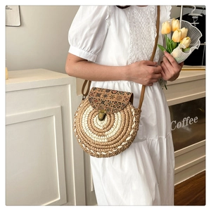 Detail of round straw crossbody bag featuring vintage ethnic print and metal clasp