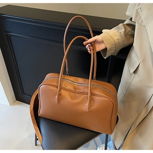 Detail of caramel brown litchi grain PU leather boston bag with silver zipper closure