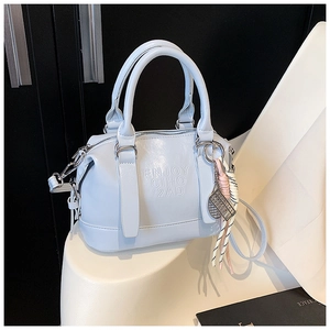 Detail of light blue soft faux leather pillow bag with debossed text and woven tassel charm
