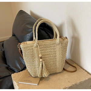Detail view of woven straw tote bag featuring hollow grid texture and brown strap