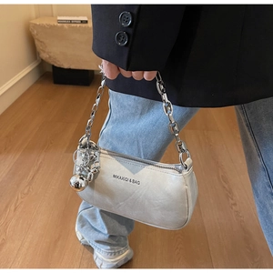 Détail du sac à bandoulière en cuir gris clair avec chaîne argentée et breloque chien mignonne