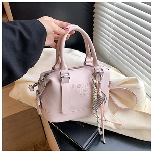 Detail of light pink soft leather pillow bag with embossed text and tassel charm accessory