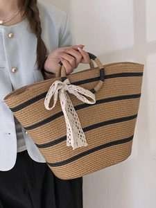 Handwoven straw tote bag with black stripes and elegant white lace ribbon bow accent