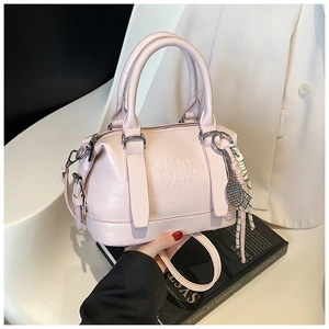 Pink leather boston bag with embossed text and woven rope charm on a suit background