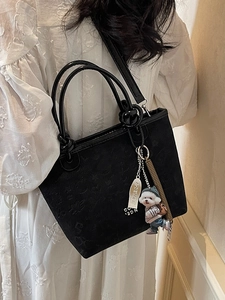 Elegant black embossed bucket bag with cute dog charm and shoulder strap for women