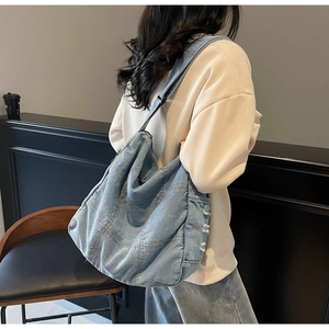 Detail of light blue washed denim crossbody bag with distressed edge craftsmanship