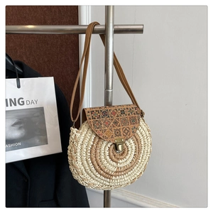 Detail of round straw crossbody bag with ethnic pattern cork flap and metal lock