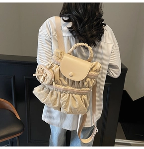 Detail of cream pleated backpack with ruffled design and matching mini bow charm bag