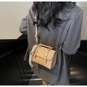 Detail view of khaki crossbody bag with silk scarf charm on a fashion model