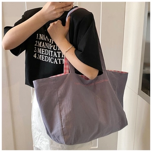 Close-up of the grey-purple canvas tote bag showing its pink and white plaid lining detail
