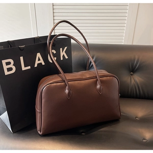 Detail of large dark brown tote bag with premium lychee grain leather texture and long handles