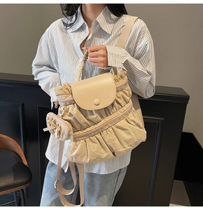 Detail of cream pleated backpack featuring a heart pouch and soft nylon texture on a model