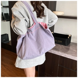 Detail of purple canvas tote bag featuring pink embroidery and plaid inner lining