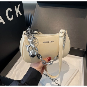 Détail d'un sac à bandoulière blanc crème avec chaîne argentée et pendentif chien ballon