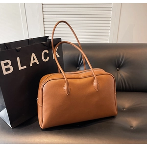 Detailed texture of brown pebble leather shoulder bag on a black sofa background
