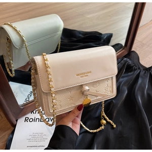 Close-up of cream white chain bag with embossed star patterns and gold logo detail
