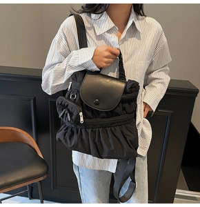 Detail view of black pleated nylon backpack with leather flap and functional zippers