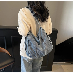 Close-up of light blue washed denim tote bag with patchwork and metal zipper detail