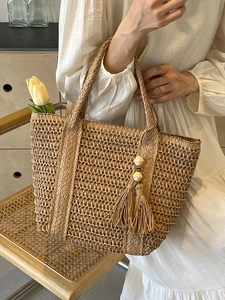 Minimalist woven straw tote bag with beaded tassel detail for summer vacation style