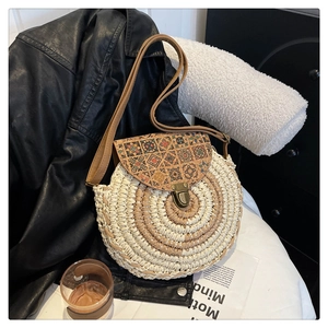 Detailed close-up of woven round straw bag with bohemian ethnic pattern and bronze clasp